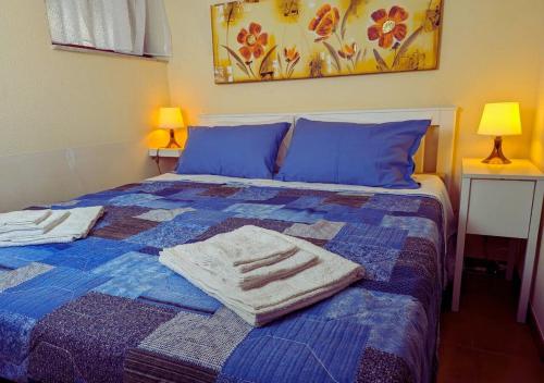 a bed with blue pillows and towels on it at Casetta indipendente MottaSant'anastasia in Motta SantʼAnastasia