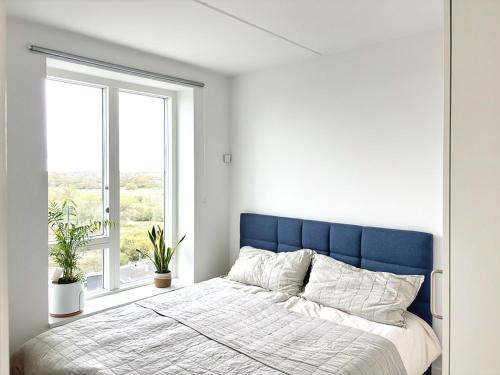 a bedroom with a blue bed and a window at Modern Apartment with Amazing Views in Copenhagen