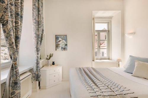 a white bedroom with a bed and two windows at Hydra Hotel in Hydra