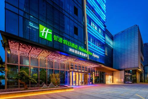 un edificio con un letrero iluminado delante de él en Holiday Inn Express Nanjing Riverside, an IHG Hotel en Nankín
