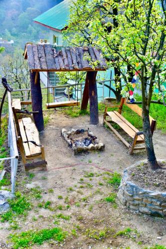 a group of picnic tables and a fire place at Manali Mist in Jagatsukh