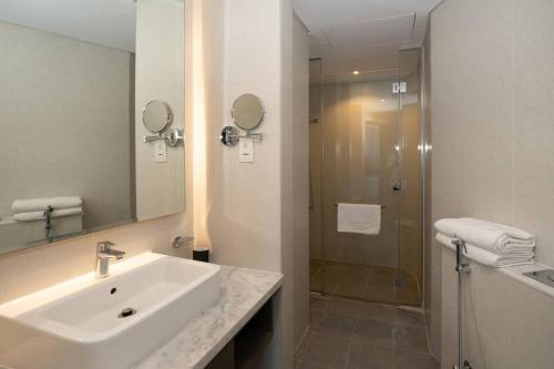 een witte badkamer met een wastafel en een douche bij Business Bay centrally located Cozy Studio in Dubai