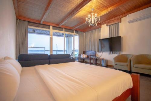 Far Falla Hotel في نانوان: غرفة نوم بسرير واريكة وتلفزيون