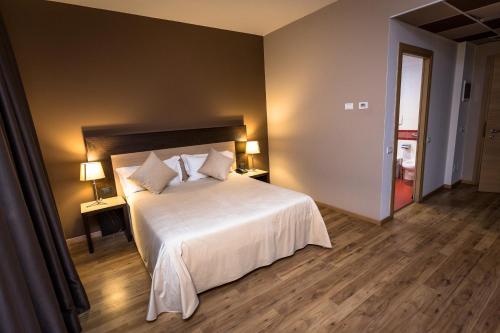 a bedroom with a large white bed with two lamps at HOTEL DON CAMILLO in Brescello