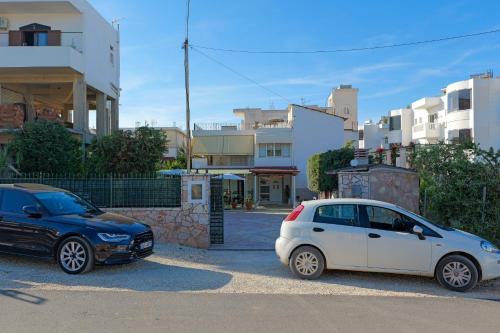 twee auto's geparkeerd op een parkeerplaats naast gebouwen bij Vila Kristian in Ksamil