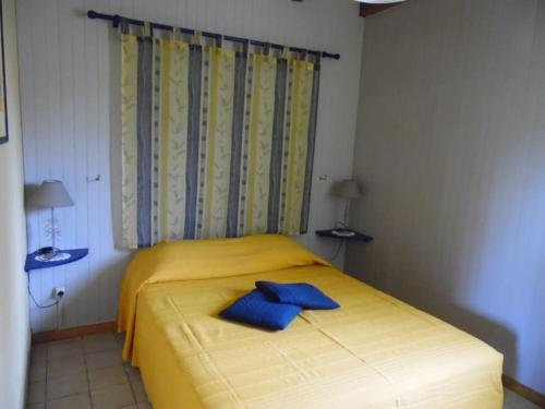 a yellow bed with two blue towels on it at Le Viognier - Gîte - Lot (vallée de la Dordogne) in Saint-Michel-de-Bannières