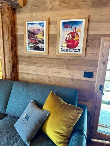a blue couch with two posters on a wall at Ad Maiora Baita Walser with SPA in Alagna Valsesia