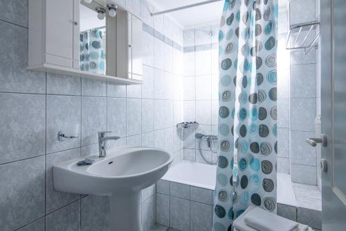 a white bathroom with a sink and a shower at Litsa Mare Apartments in Agia Pelagia