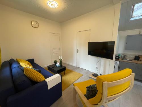un salon avec un canapé bleu et une télévision dans l'établissement Maison paisible et élégante JO CDG, à Aulnay-sous-Bois