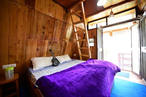 sypialnia z łóżkiem z fioletową kołdrą i drabiną w obiekcie JOYstels Manali w mieście Manāli