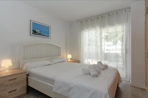 a white bedroom with a bed and a window at Apartment Alva Lloretholiday in Lloret de Mar