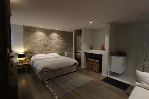 sypialnia z łóżkiem i kamienną ścianą w obiekcie Marie aux Champs w mieście Dolembreux