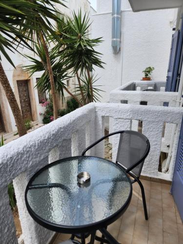 a glass table and a chair on a balcony at Eleios Hotel Serifos in Livadi