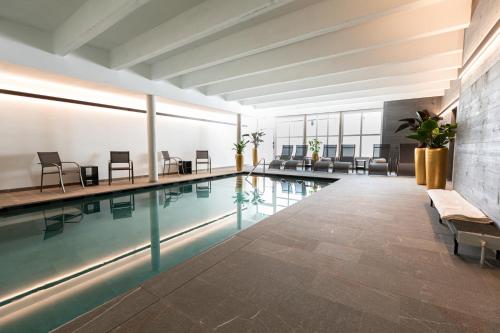 basen w budynku z krzesłami i stołami w obiekcie Sporthotel Igls w mieście Innsbruck