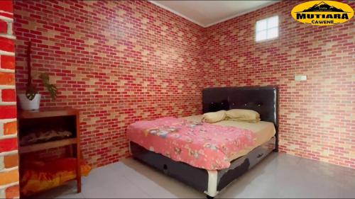 a bedroom with a brick wall with a bed in it at Villa Mutiara Cawene in Gunungpicung