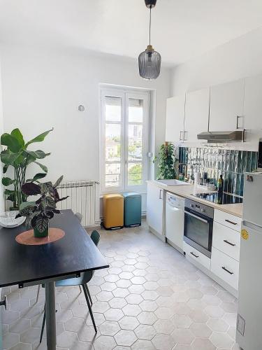 une cuisine avec des armoires blanches et une table avec une plante en pot dans l'établissement Spacieux T3 80m2 plein centre presque ile !, à Lyon