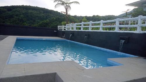 a large swimming pool with a white fence around it at Villa Mutiara Cawene in Gunungpicung