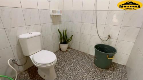 a bathroom with a toilet and a green trash can at Villa Mutiara Cawene in Gunungpicung