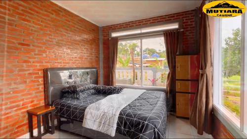 a bedroom with a bed and a brick wall at Villa Mutiara Cawene in Gunungpicung