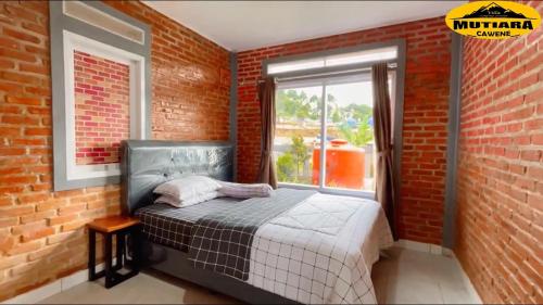 a bedroom with a bed in a brick wall at Villa Mutiara Cawene in Gunungpicung