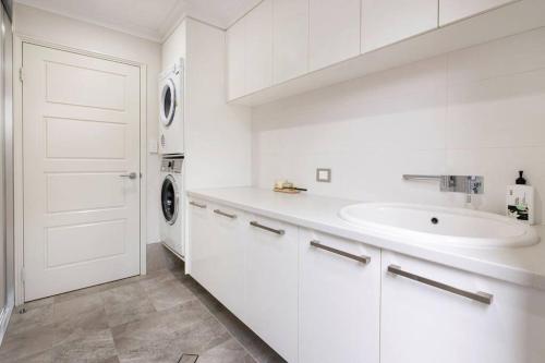 a white bathroom with a sink and a washing machine at The Bay Retreat in Dunsborough