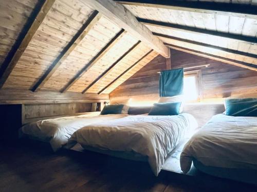 two beds in a room with wooden walls at Le Chalet Georges in Chamonix