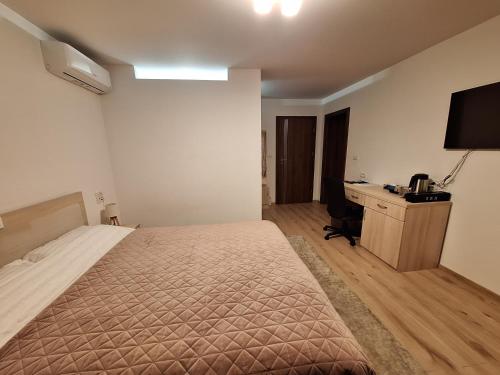 a bedroom with a bed and a desk with a computer at TREND - cazare, gradina, piscina in Arad