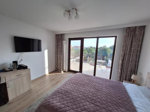 a bedroom with a bed and a sliding glass door at TREND - cazare, gradina, piscina in Arad