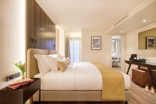 a bedroom with a large white bed and a desk at Hotel Moon & Sun Lisboa in Lisbon