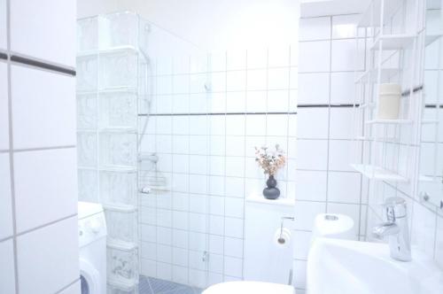 uma casa de banho em azulejos brancos com um WC e um lavatório em Serviced Luxury Apartment in Østerbro - incl housekeeping once a week em Copenhague