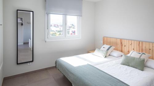 ein Schlafzimmer mit einem großen Bett und einem Spiegel in der Unterkunft AG Casa do Ramon en Playa Razo con patio exterior in A Coruña