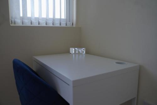a white table with a blue chair and a window at Luxury Apartment in Luton in Luton