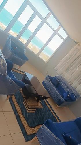 a living room with a large window and blue chairs at Jean d’arc in Skikda