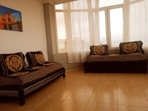 a living room with two couches and two windows at Jean d’arc in Skikda