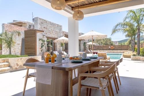 una cocina al aire libre con mesa y sillas y una piscina en White Stone Luxury Villa en Lithakia