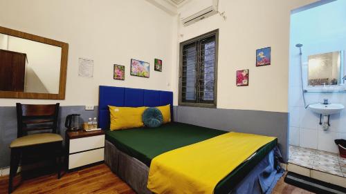 1 dormitorio con cama amarilla y azul y lavamanos en Hanoi Cozy Homestay Long Biên, en Hanói
