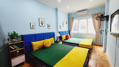 een slaapkamer met twee bedden met blauw en geel bij Hanoi Cozy Homestay Long Biên in Hanoi