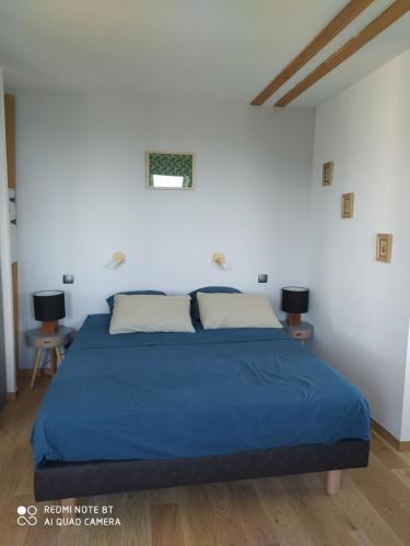 une chambre avec un lit bleu dans une pièce blanche dans l'établissement Gîte de la chabanne, à Lentillères