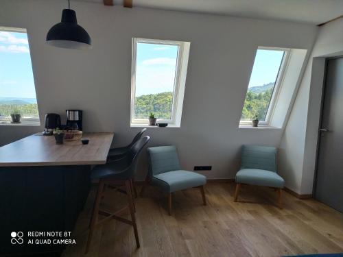 - une cuisine avec une table et deux chaises et des fenêtres dans l'établissement Gîte de la chabanne, à Lentillères