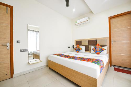 a bedroom with a large bed with colorful pillows at FabEscape Panchkula Motels in Panchkula