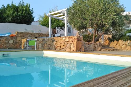 a swimming pool in a yard with a stone wall at Villa La Samia in Torricella