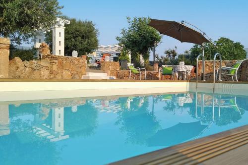 a swimming pool with an umbrella and a table and chairs at Villa La Samia in Torricella