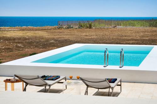 einen Pool mit zwei Stühlen und zwei Wasserhähnen in der Unterkunft Villa Capo Passero in Portopalo