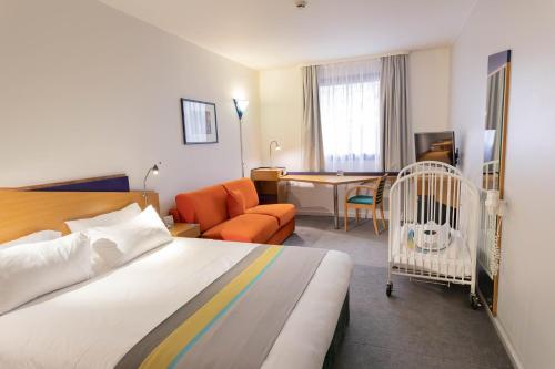 Holiday Inn Express Arras, an IHG Hotel في أراس: غرفه فندقيه بسرير وكرسي وسرير اطفال