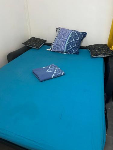 una cama azul con almohadas encima en Joli bungalow fleuri, en Les Abymes