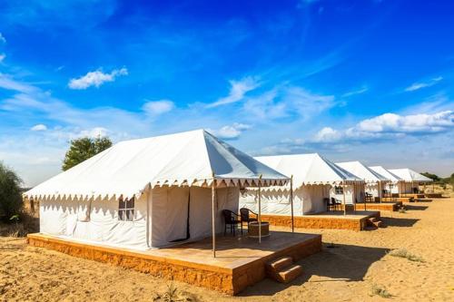 Une rangée de tentes blanches dans le désert dans l'établissement Jaisalmer Night Safari Camp, à Jaisalmer