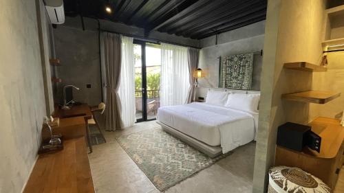 a bedroom with a white bed and a window at Leafy Lofts Canggu in Canggu