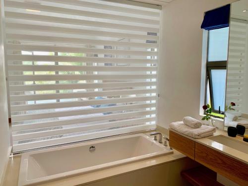 a bathroom with a bath tub and a window with blinds at Luxury Apartment on the Beach in Belle Mare