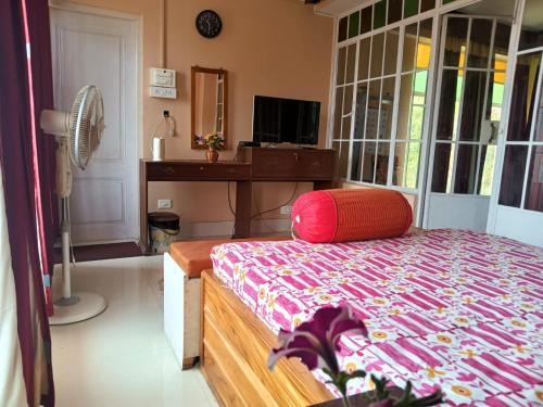 a bedroom with a bed and a desk with a fan at SAI´S GRACE in Kalimpong