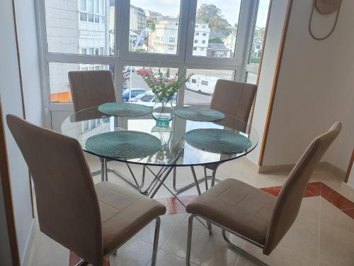 a glass table with four chairs and a vase with flowers at Mirasol in Viveiro